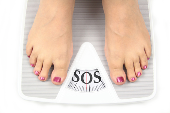 Femme sur une balance avec écrit 'SOS'